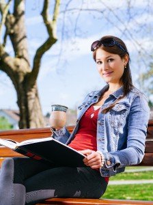 Beautiful Woman Drinking And Reading On Park Bench