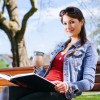 Beautiful Woman Drinking And Reading On Park Bench